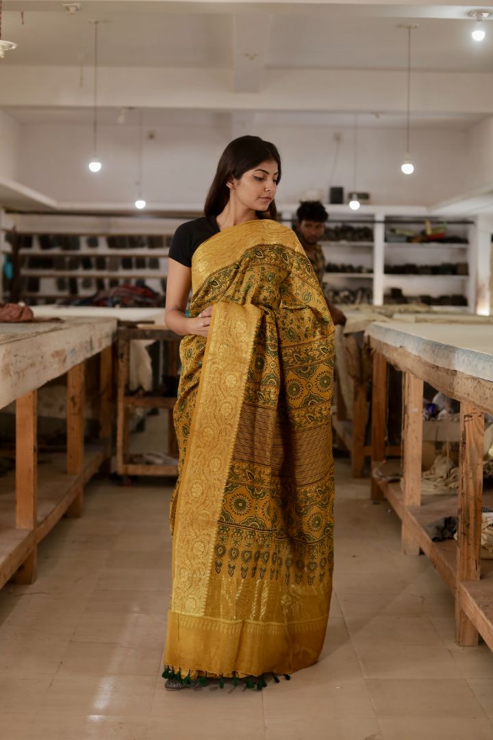 Antique gold Ajrakh Chanderi silk saree featuring traditional hand block printed motifs and a shimmering zari border