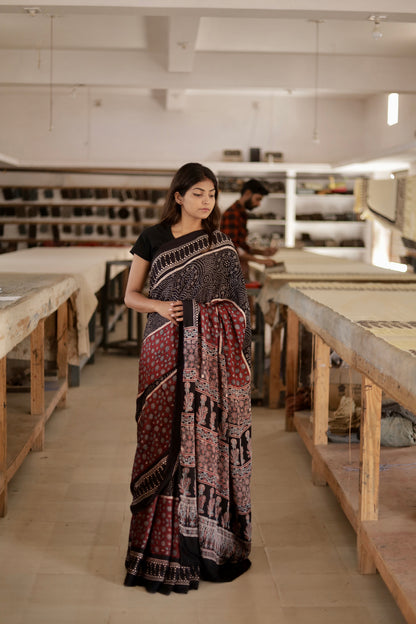 Black and maroon Ajrakh modal silk saree featuring intricate hand block printed motifs and a graceful drape