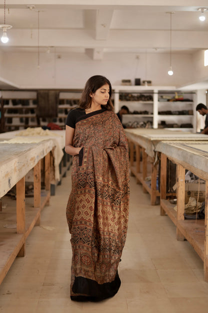 Caramel brown Ajrakh modal silk saree featuring intricate hand block printed motifs and a graceful drape