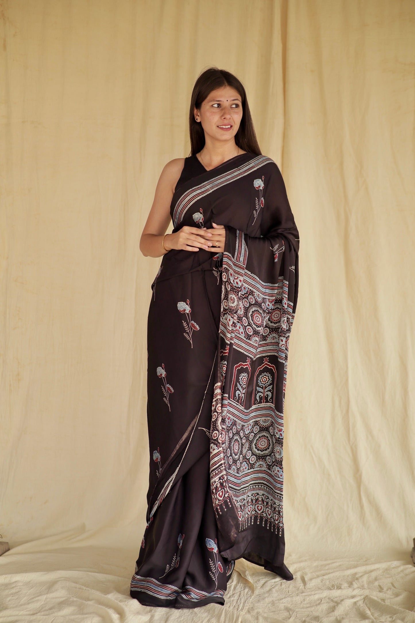 Charcoal black Ajrakh modal silk saree featuring intricate hand block printed motifs and a graceful drape