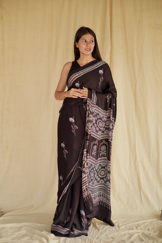 Charcoal black Ajrakh modal silk saree featuring intricate hand block printed motifs and a graceful drape