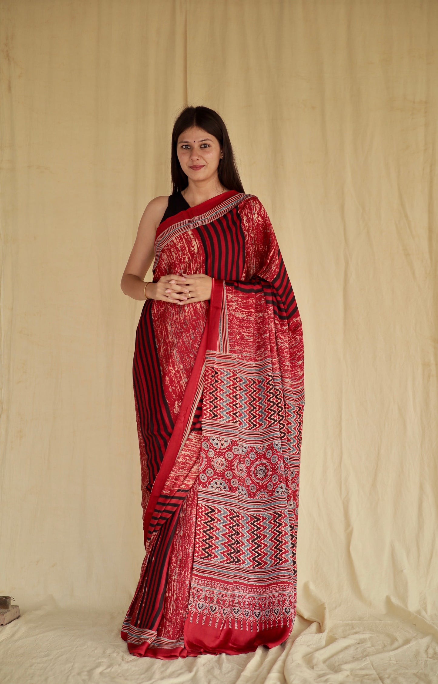 Cherry red Ajrakh modal silk saree featuring intricate hand block printed motifs and a graceful drape