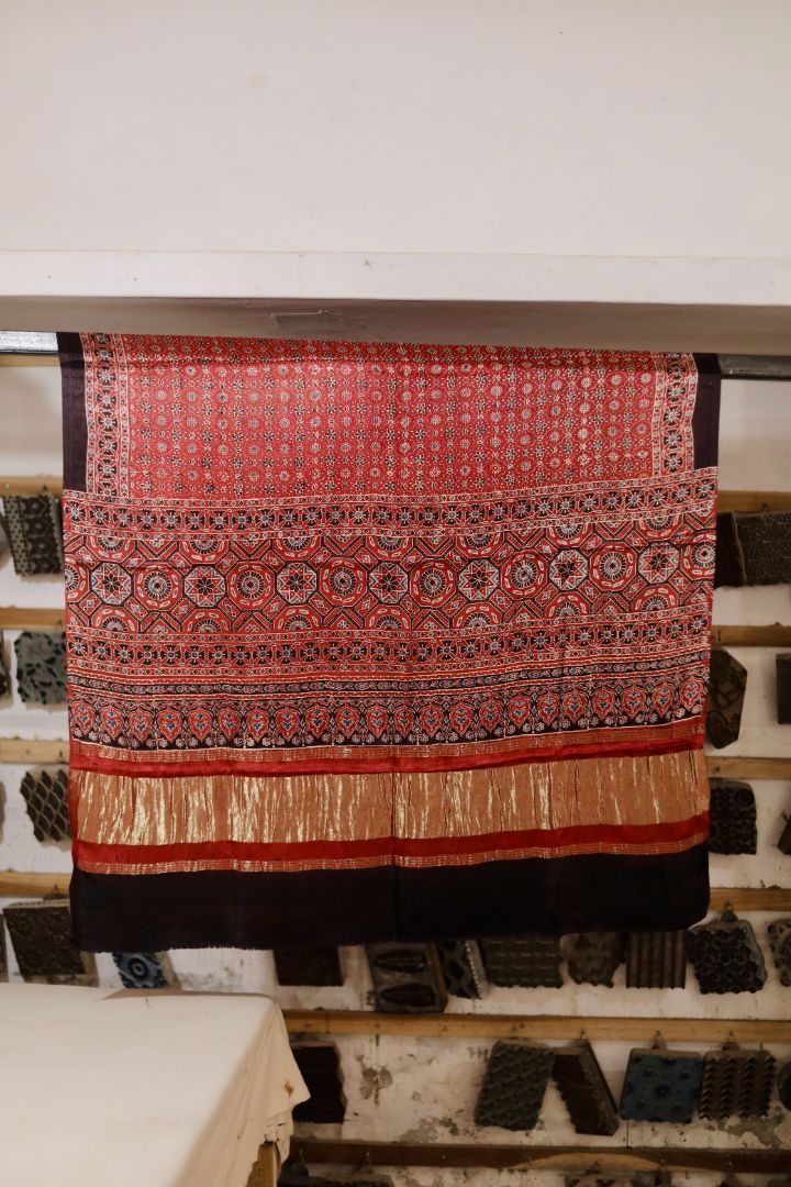 Coral red Ajrakh modal silk dupatta with Lagdi Patta featuring intricate block printed motifs and elegant drape