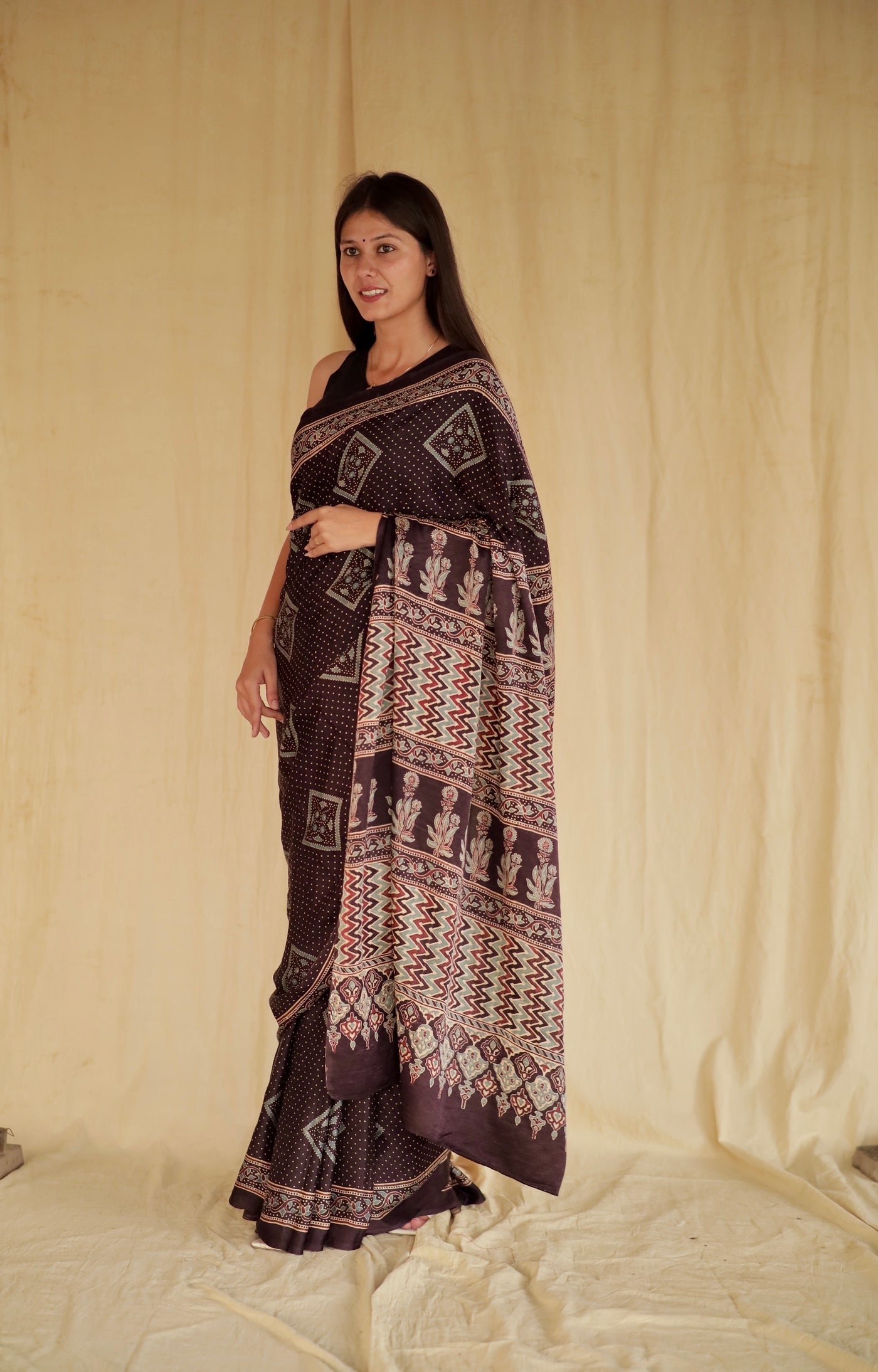 Deep black Ajrakh modal silk saree featuring intricate hand block printed motifs and a graceful drape