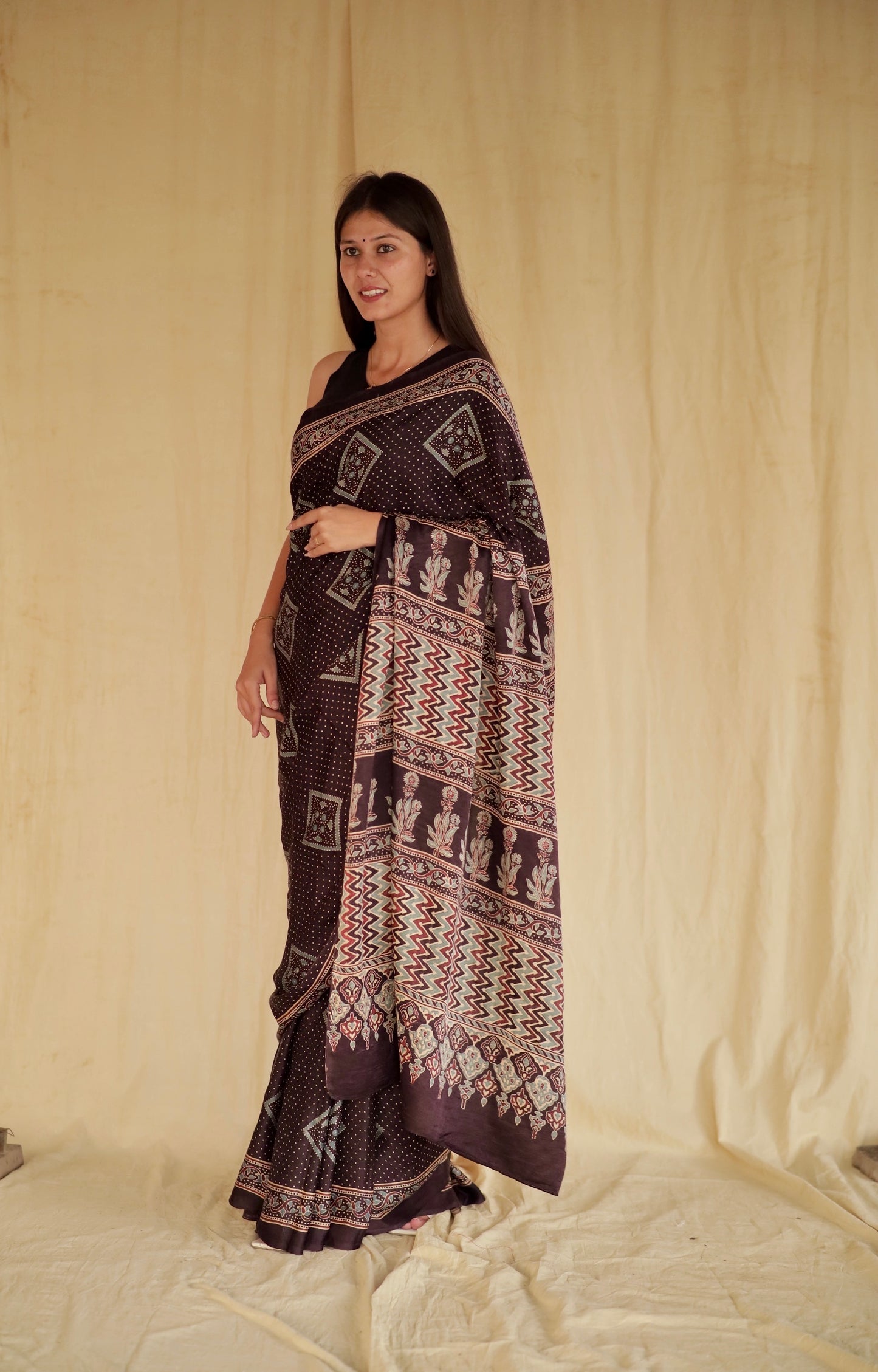 Deep black Ajrakh modal silk saree featuring intricate hand block printed motifs and a graceful drape