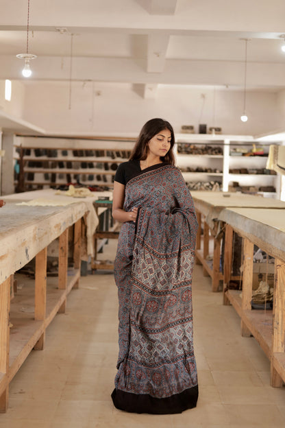 Dusty blue Ajrakh modal silk saree featuring intricate hand block printed motifs and a graceful drape