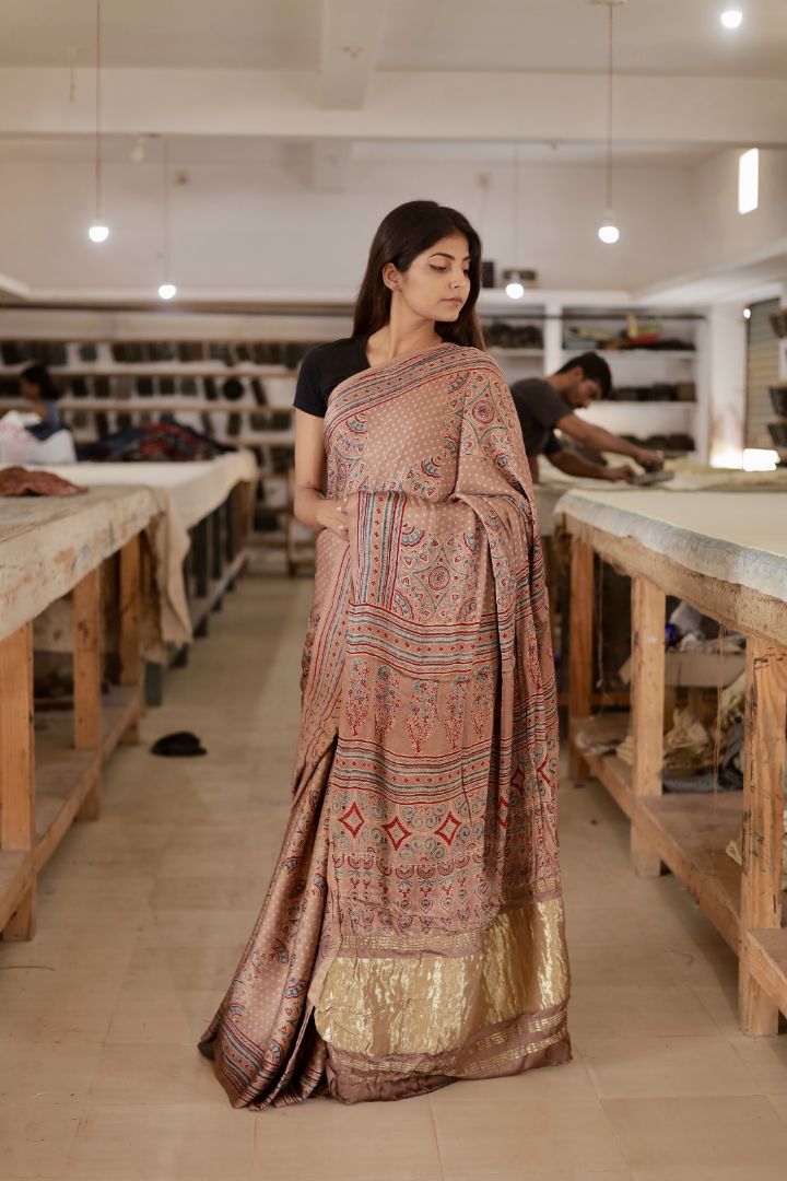 Dusty brown Ajrakh modal silk saree featuring intricate hand block printed motifs and an elegant zari border