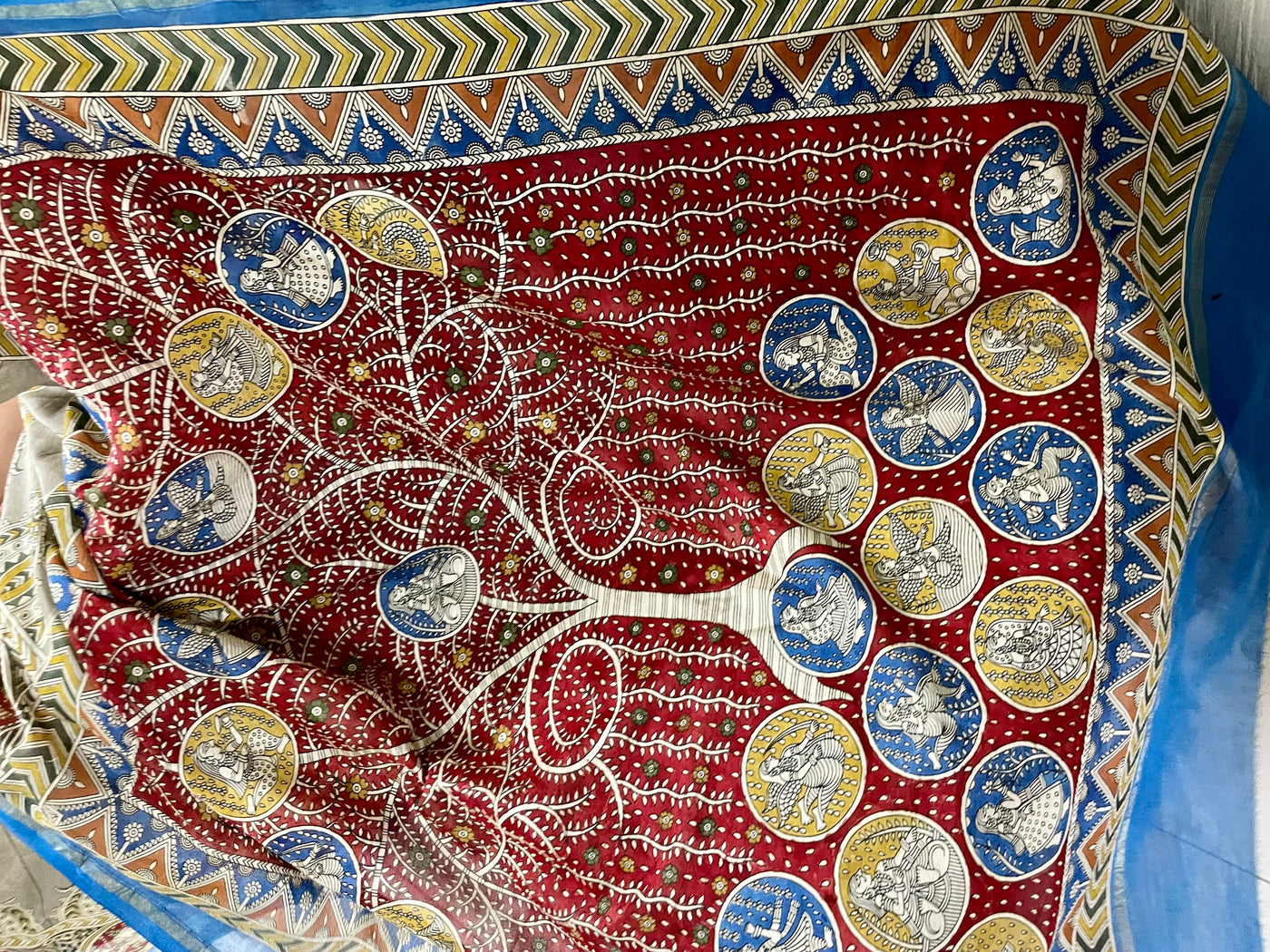Elegant creamy red saree showcasing detailed Mata Ni Pachedi artwork created by skilled artisans