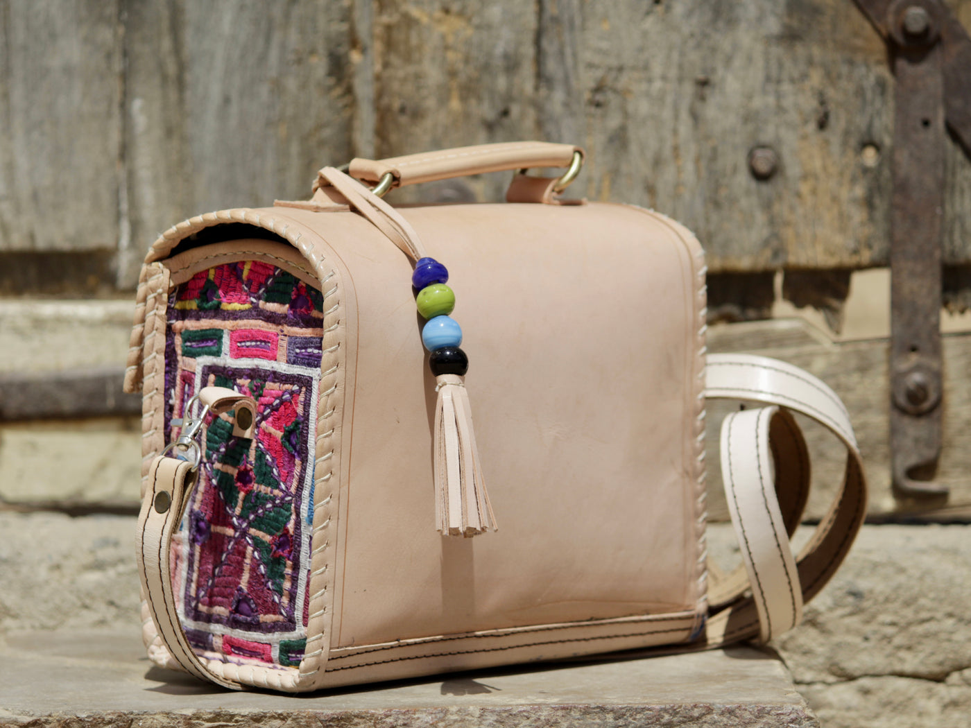 Artisan-made leather hut bag featuring decorative thread embroidery on premium leather