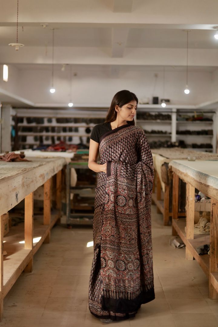 Traditional charcoal black Ajrakh modal silk saree with rich artisanal prints and a soft flowing texture