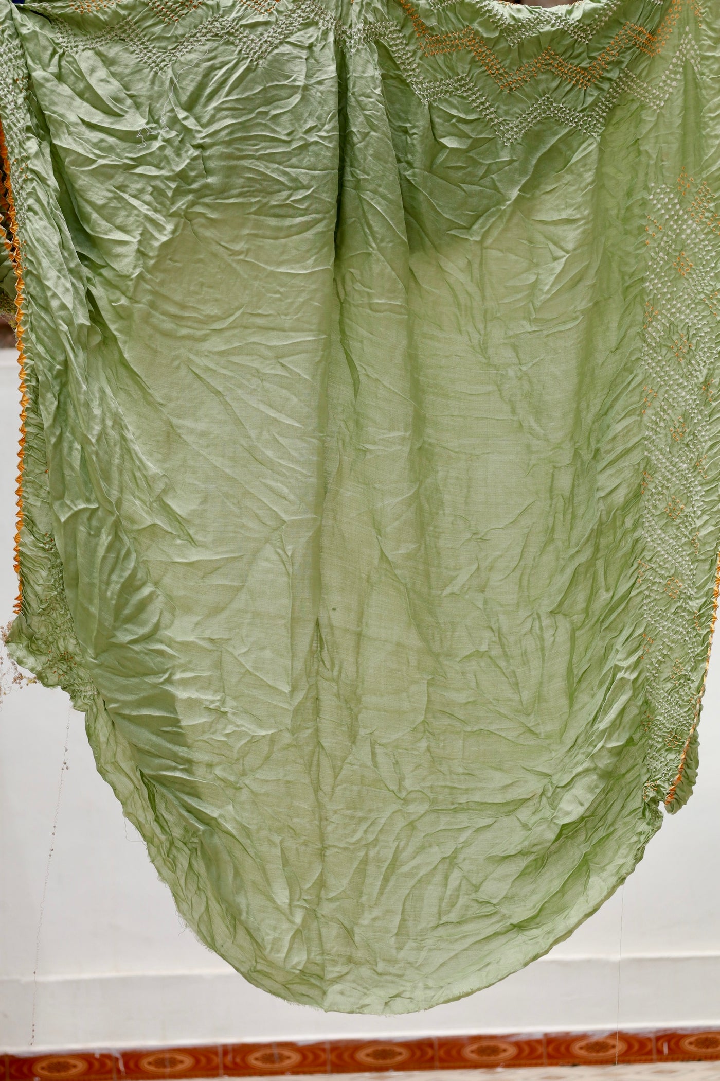 Premium sage green Rai Bandhani silk saree highlighting fine artisan craftsmanship and festive elegance