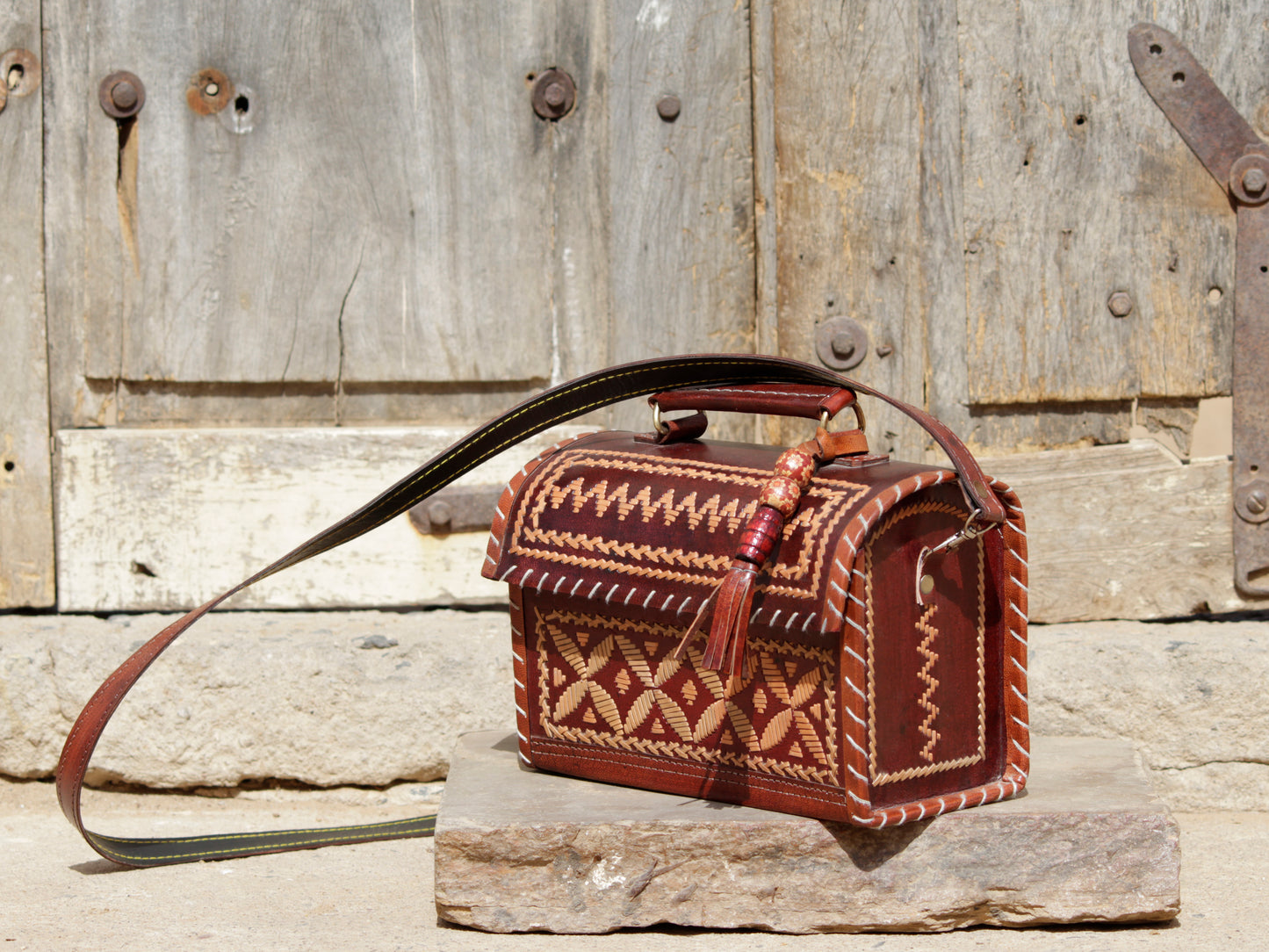 Leather hut bag featuring intricate handcrafted thread work on premium leather