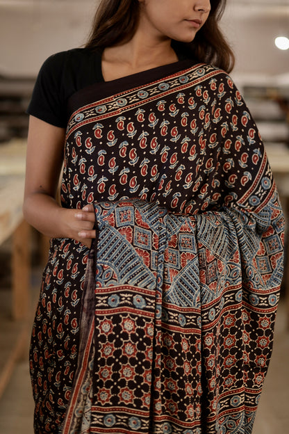 Handcrafted black modal silk saree adorned with traditional Ajrakh patterns and elegant zari detailing