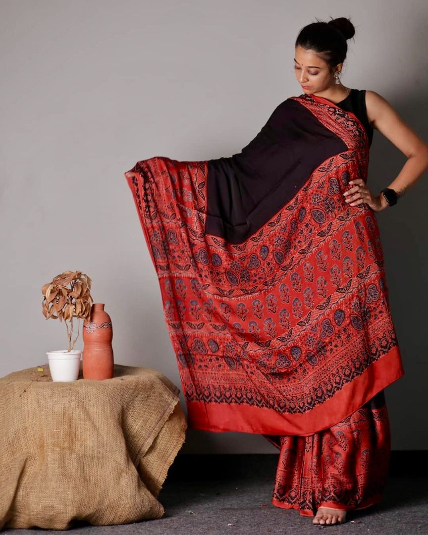 Handcrafted black modal silk saree adorned with vibrant red Ajrakh motifs and elegant drape
