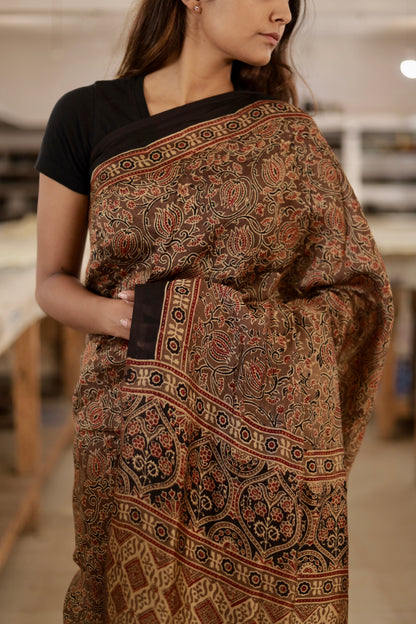 Handcrafted caramel brown modal silk saree adorned with traditional Ajrakh patterns and artisanal detailing