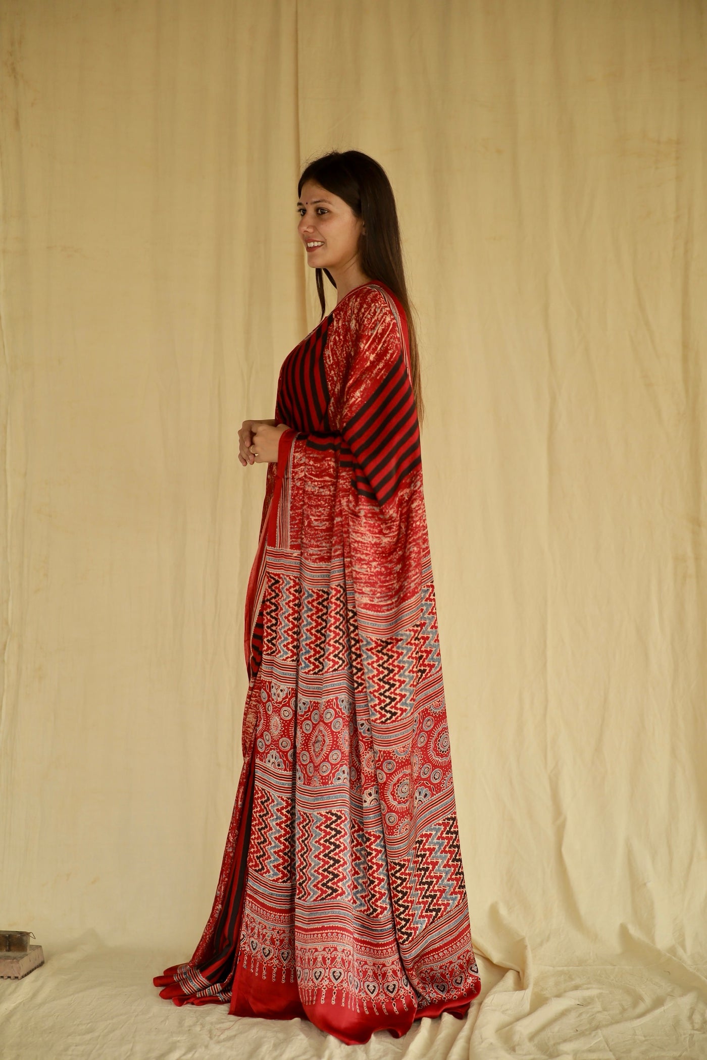 Handcrafted cherry red modal silk saree adorned with traditional Ajrakh patterns and refined detailing.