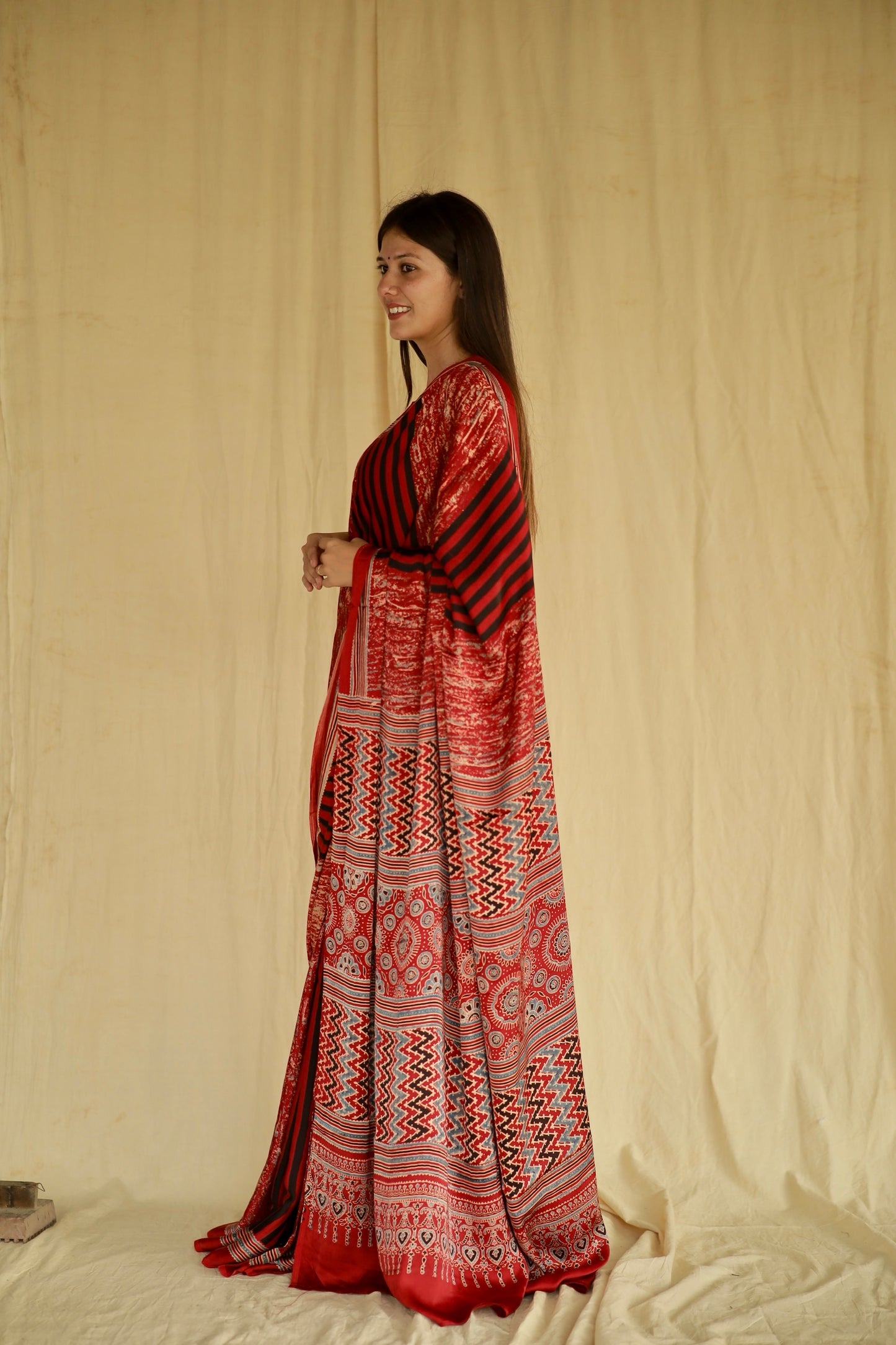 Handcrafted cherry red modal silk saree adorned with traditional Ajrakh patterns and refined detailing.