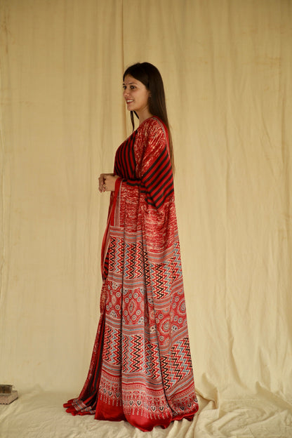 Handcrafted cherry red modal silk saree adorned with traditional Ajrakh patterns and refined detailing.
