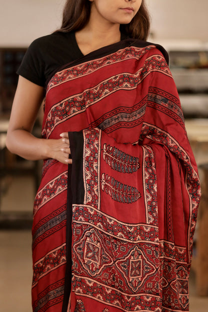 Handcrafted deep garnet modal silk saree adorned with traditional Ajrakh patterns and artisanal detailing