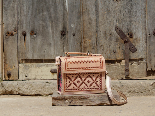 Leather hut bag adorned with intricate handcrafted thread work and traditional detailing