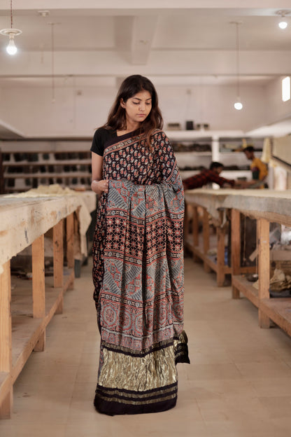 Premium black modal silk saree showcasing authentic Ajrakh craftsmanship and festive zari work