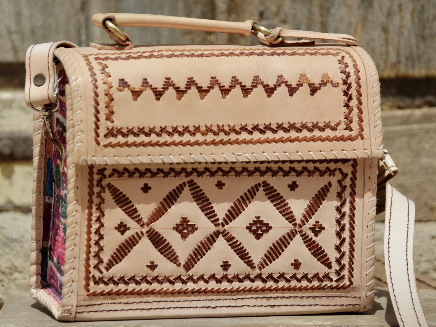 Artisan-made leather hut bag featuring decorative thread embroidery on premium leather