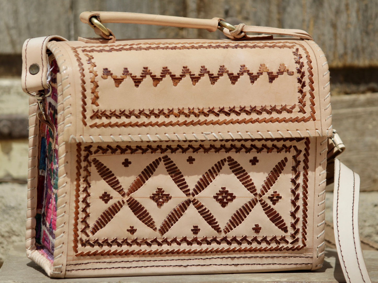 Artisan-made leather hut bag featuring decorative thread embroidery on premium leather