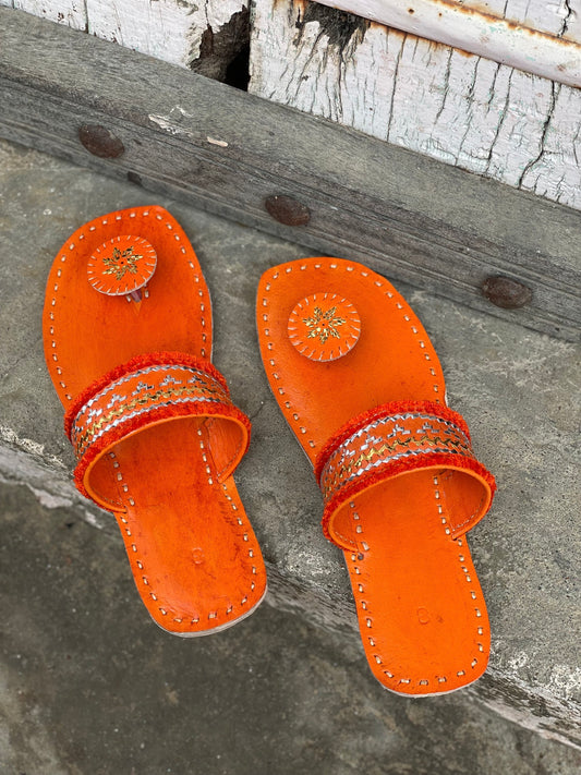 Orange handstitched leather flats showcasing traditional craftsmanship and comfortable design