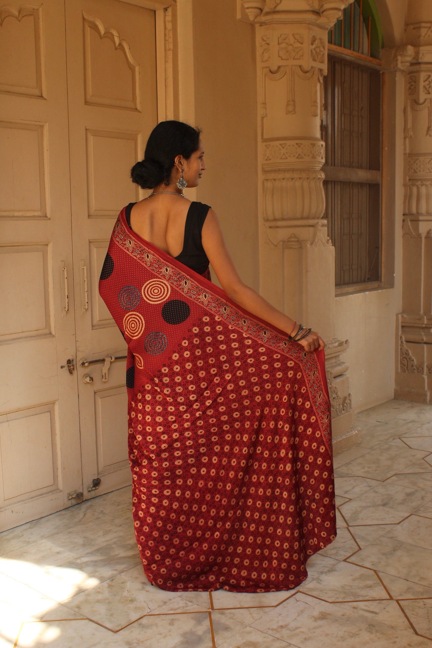 Premium brick red modal silk saree with heritage-inspired Ajrakh designs and fluid texture