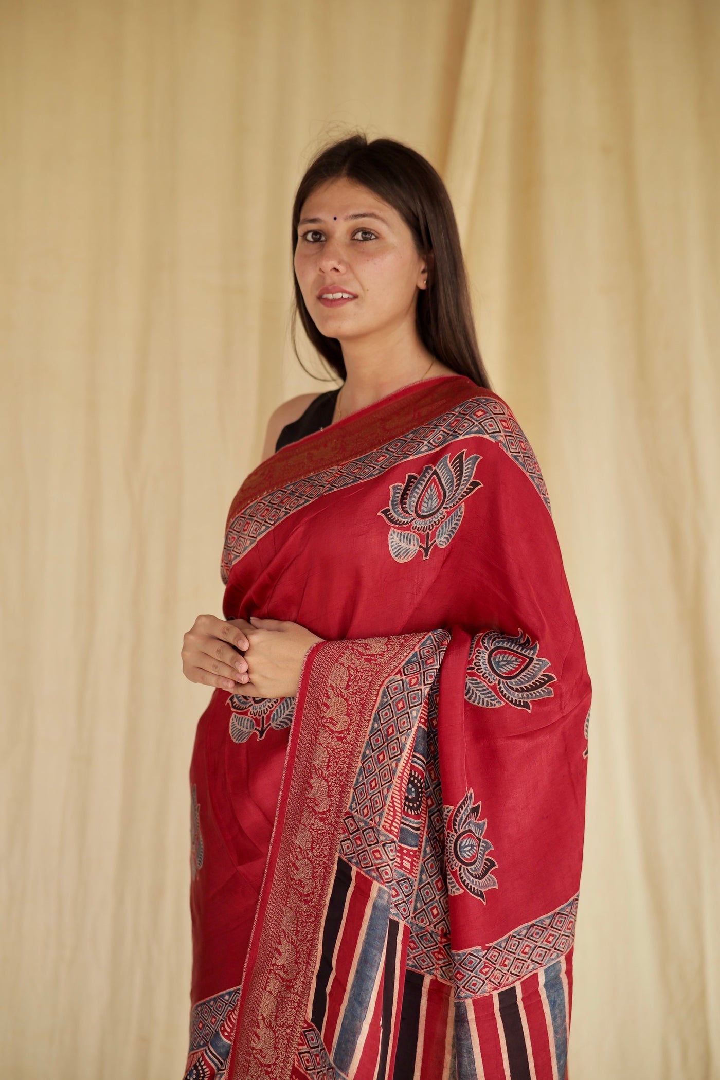 Premium crimson red Dola silk saree showcasing heritage-inspired Ajrakh designs and fluid fall