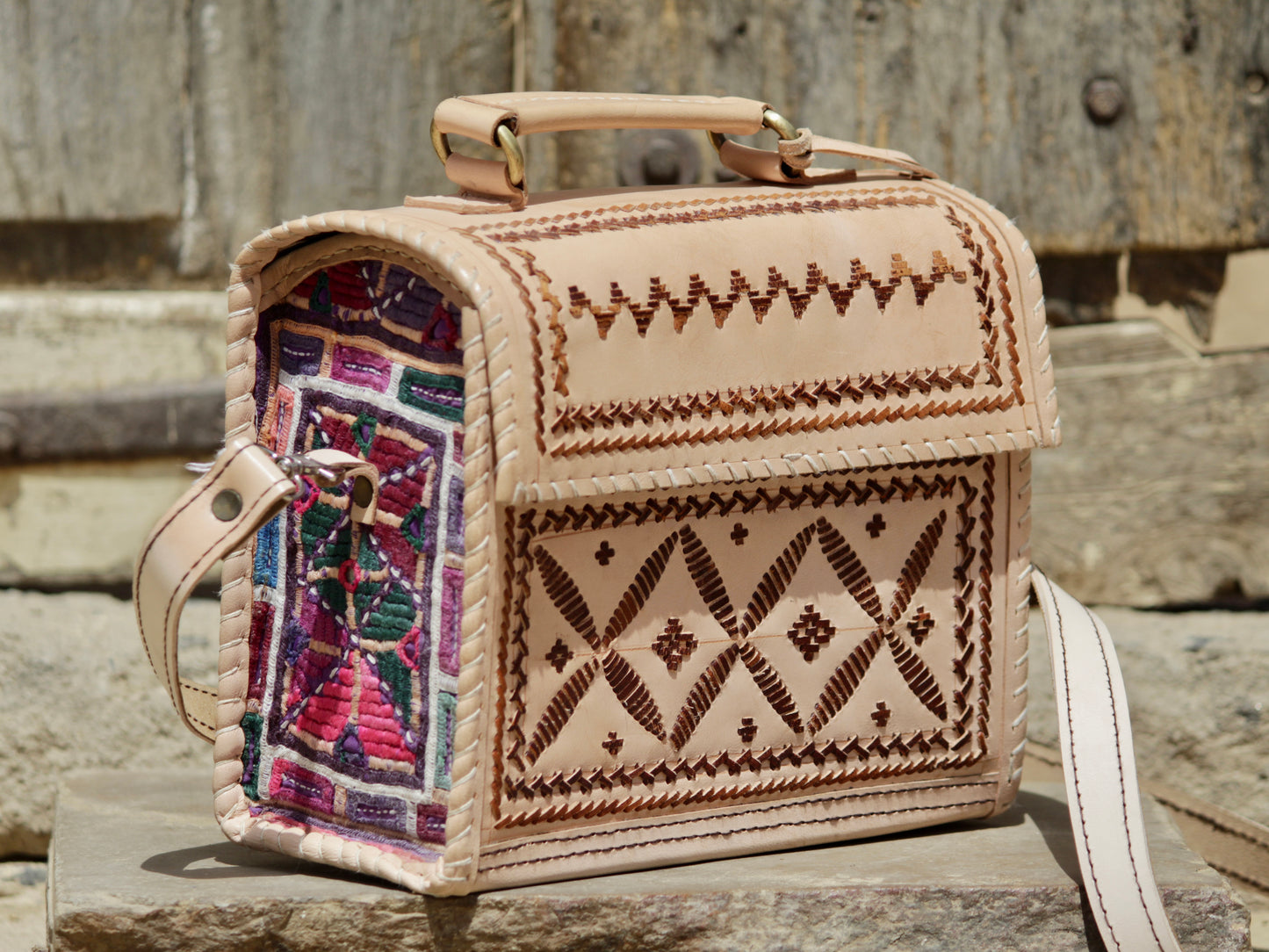 Artisan-made leather hut bag featuring decorative thread embroidery on premium leather