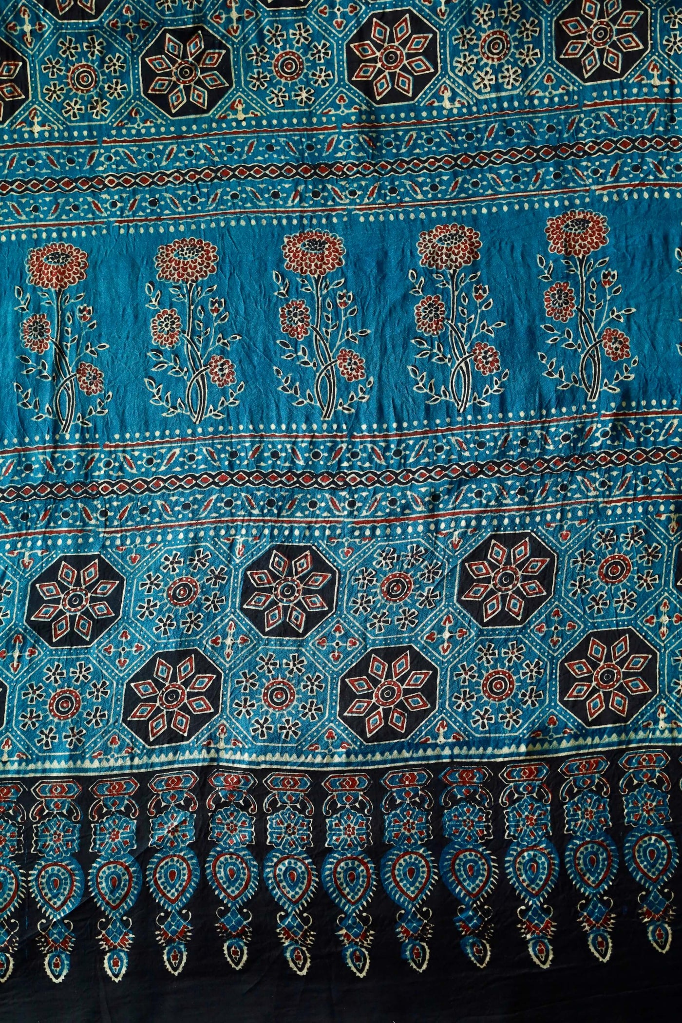 Turquoise blue Ajrakh modal silk saree featuring intricate hand block printed motifs and a graceful drape