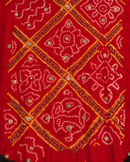Close-up of gota patti work on black and red Bandhani dupatta