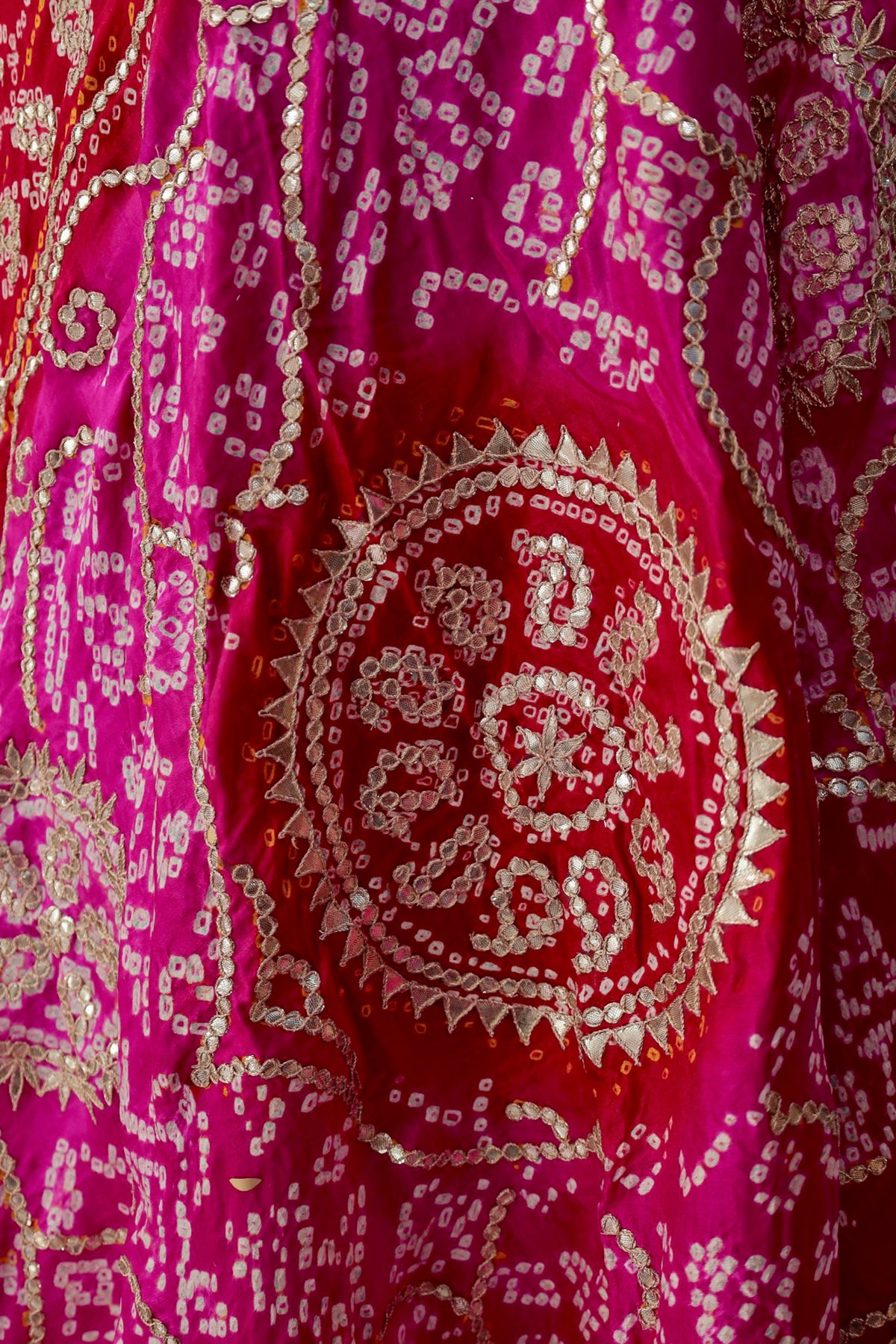 Circular floral Gota Patti medallions surrounded by curling Bandhani patterns on pink 
